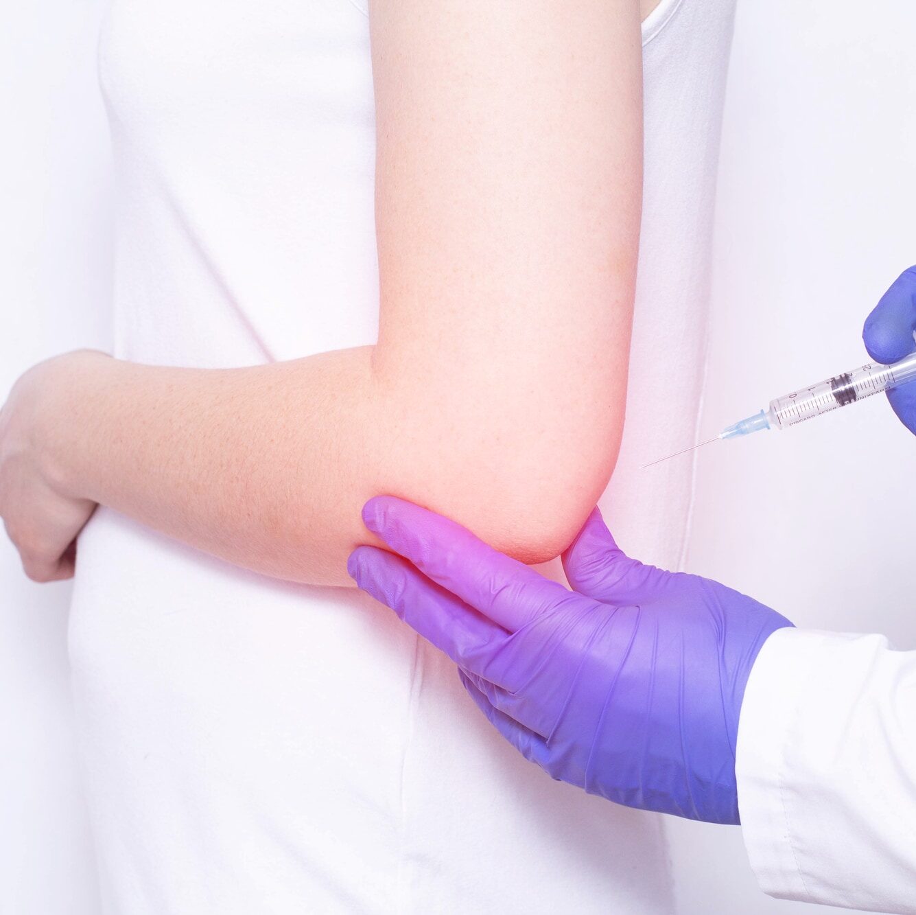 Doctor injects blockade of chondroprotector and ozone therapy to a young girl in a sore elbow joint, close-up, inflammation