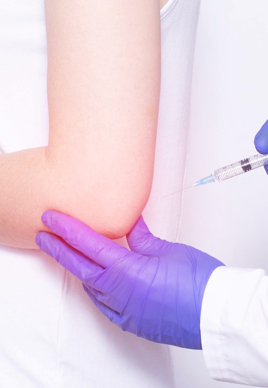 Doctor injects blockade of chondroprotector and ozone therapy to a young girl in a sore elbow joint, close-up, inflammation