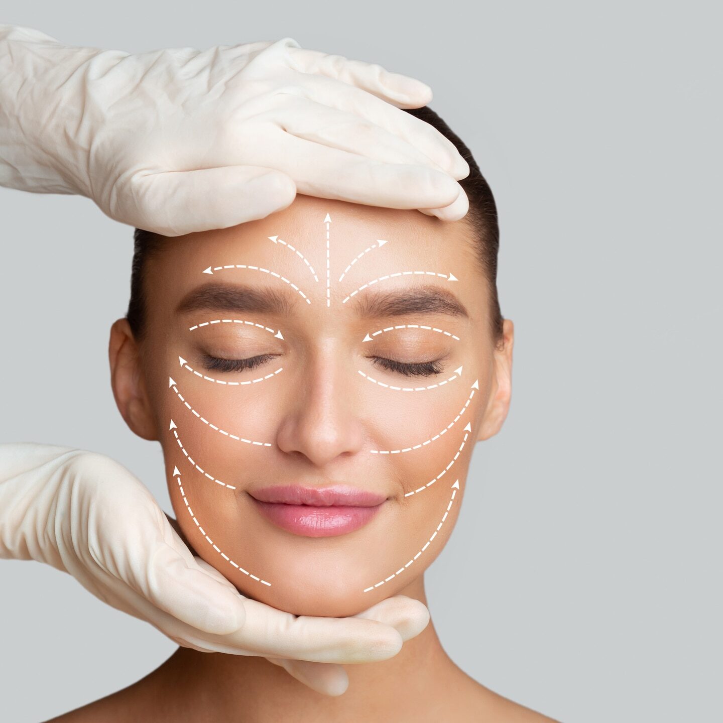 Frontal portrait of woman getting spa treatment from beautician in protective gloves, isolated on gray studio wall, copy space
