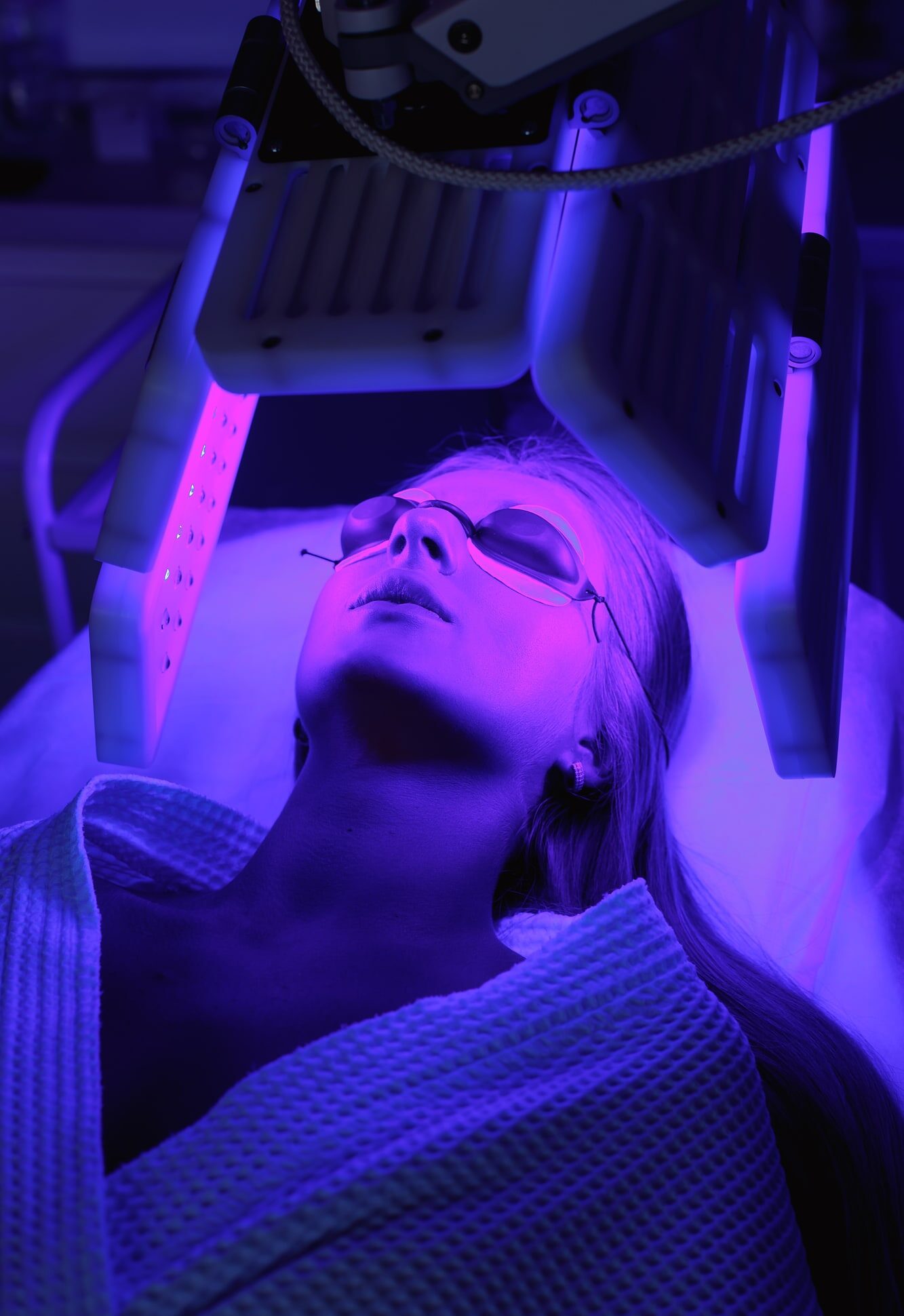 Young woman having LED light facial treatment in beauty salon. Chromotherapy, heleo4