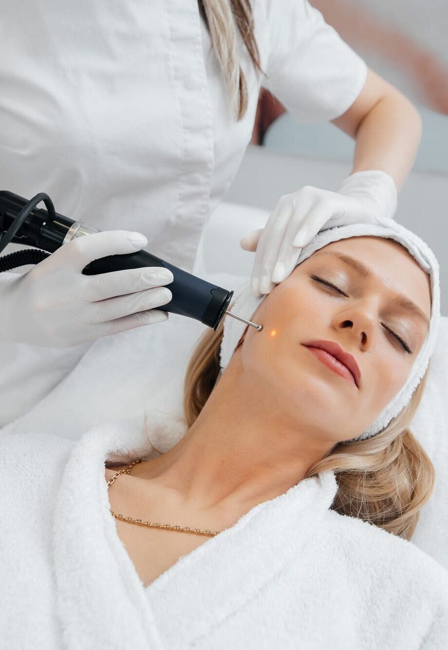 A young girl gets a charcoal peeling for the skin of the face in a beauty salon. Laser pulses cleanse the skin. Hardware cosmetology. The process of photothermolysis, warming the skin.