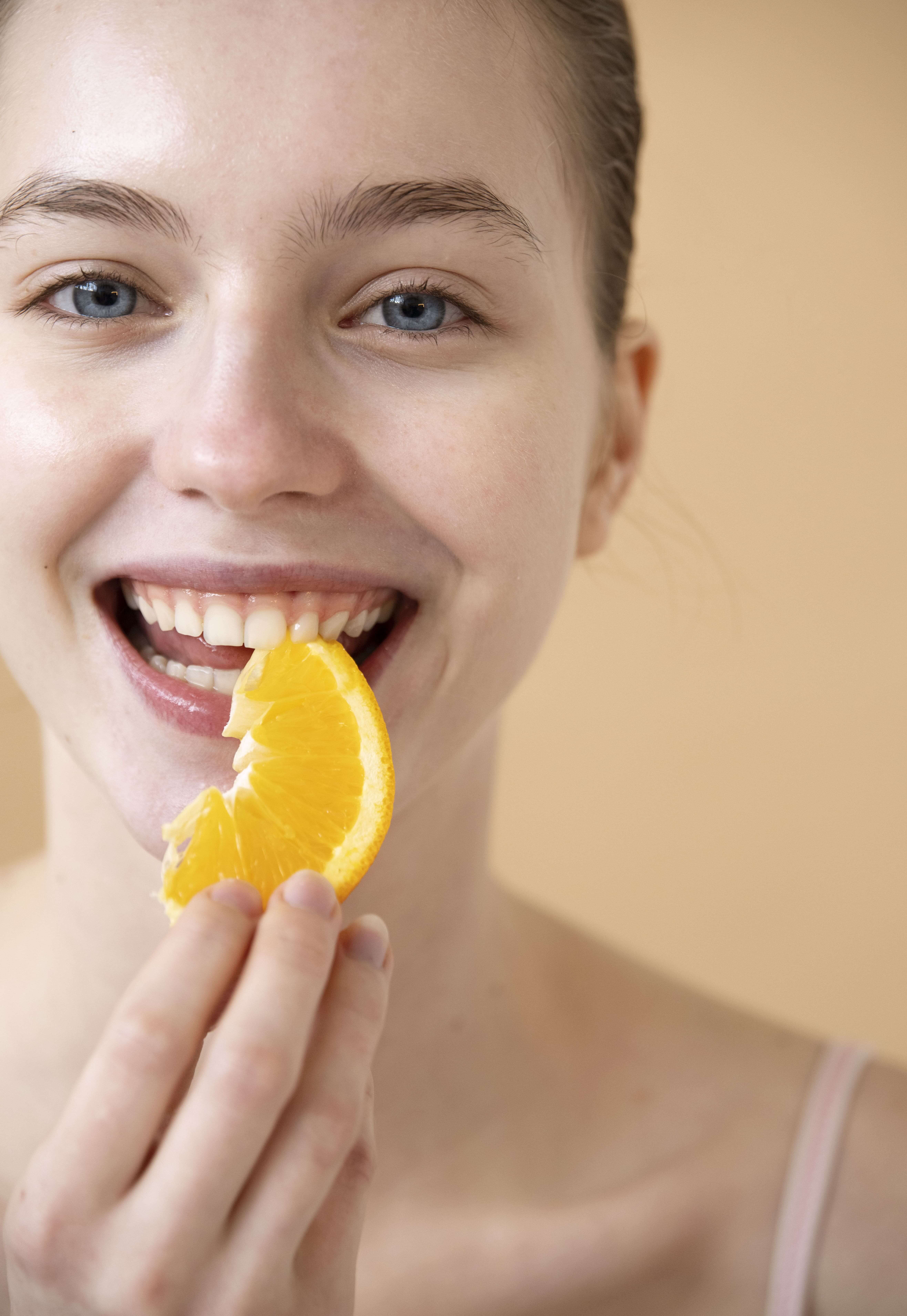 front-view-smiley-woman-eating-orange (1)